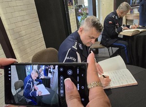 Na zdjęciu mundurowy w trakcie wpisywania do pamiątkowej księgi