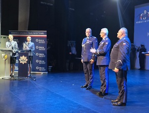 na scenie komendant wojewódzki, miejski i jego zastępca, obok przy mównicy dwie policjantki