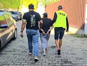 na zdjęciu kobieta w kajdankach, prowadzona przez nieumundurowanych policjantów