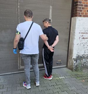 na zdjęciu nieumundurowany policjant trzyma mężczyznę w kajdankach