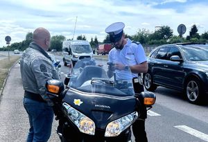 na zdjęciu policjant w trakcie kontroli motocyklisty