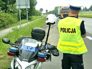 na zdjęciu policjant przy motocyklu służbowym wykonujący pomiar prędkości