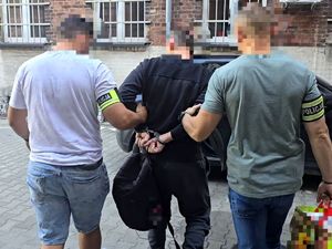 na zdjęciu zatrzymany w kajdankach trzymany przed dwóch nieumundurowanych policjantów