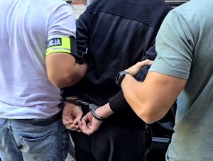 na zdjęciu zatrzymany w kajdankach trzymany przed dwóch nieumundurowanych policjantów