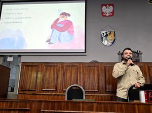 na zdjęciu policyjny psycholog w trakcie przemowy, trzyma mikrofon przy ustach