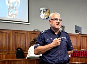 na zdjęciu zastępca komendanta w trakcie przemowy, trzyma mikrofon przy ustach