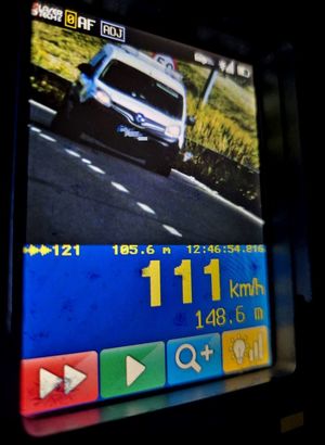 ekran urządzenia do pomiaru prędkości, na nim biały samochód osobowy i pomiar 111 kilometrów na godzinę