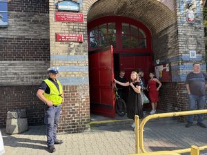 na zdjęciu policjant przy budynku szkoły
