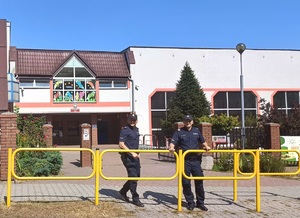 na zdjęciu dwaj policjanci przy budynku szkoły