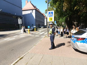 na zdjęciu policjant przy przejściu dla pieszych, obok dzieci