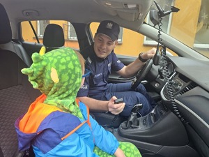 na zdjęciu w radiowozie policjant obok niego chłopiec