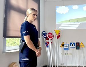 na zdjęciu policjantka obok znaków drogowych