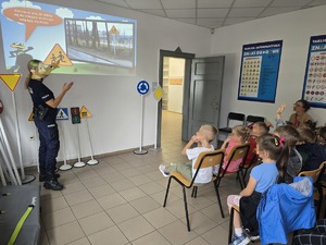 na zdjęciu policjantka, obok dzieci siedzące na krzesłach