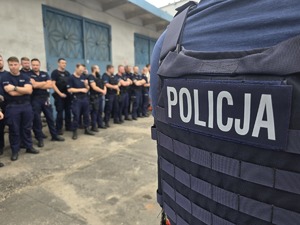 na zdjęciu kamizelka policyjna, obok policjanci w szeregu