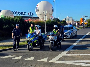 na zdjęciu policjanci drogówki, dwóch na motocyklach, za nimi radiowóz