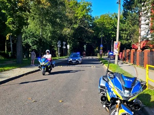policjant jadący na motocyklu, zanim radiowóz
