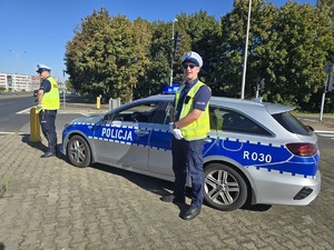 na zdjęciu radiowóz policyjny, przy nim dwóch policjantów drogówki