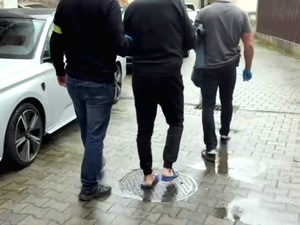 na zdjęciu zatrzymany prowadzony przez dwóch nieumundurowanych policjantów