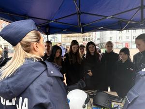 policjantka przy stoisku profilaktycznym i zgromadzone osoby