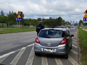 na zdjęciu policjant drogówki przy samochodzie osobowym koloru srebrnego