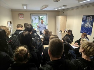 na zdjęciu licealiści w czarnych strojach, przed nimi mężczyzna