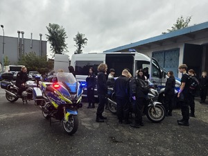 na zdjęciu na zewnątrz budynku pojazdy służbowe, motocykle służbowe na nich uczniowie klasy mundurowej