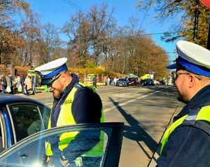 na zdjęciu policjanci przy samochodzie obok cmentarza