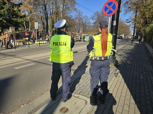 na zdjęciu policjant i strażniczka miejska obok cmentarza