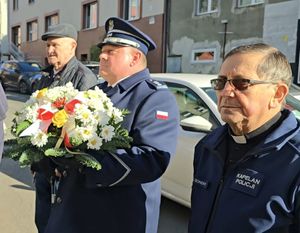 na zdjęciu kapelan, komendant, który trzyma kwiaty, obok starszy mężczyzna