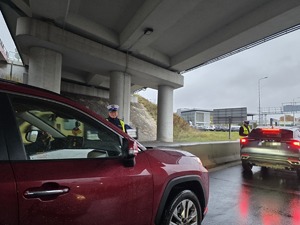 na zdjęciu policjanci obok pojazdów, badają trzeźwość kierujących