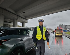 na zdjęciu policjanci na jezdni obok pojazdów, badają trzeźwość kierujących