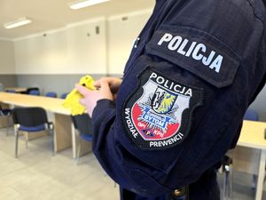 na zdjęciu ramię policjanta, w dłoni trzyma paralizator żółtego koloru