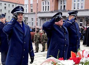 na zdjęciu komendant i dwóch oficerów salutujący przed pomnikiem
