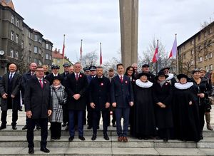 na zdjęciu osoby pozujące do zdjęcia, stojące przed pomnikiem Wolności