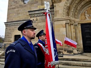 na zdjęciu policjanci ze sztandarem stojący przed kościołem