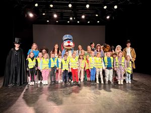 na zdjęciu aktorzy, Sznupek i dzieci w kamizelkach odblaskowych na scenie pozujący do fotografii