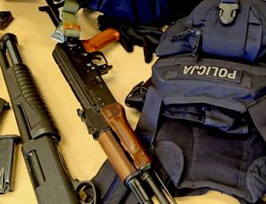 na zdjęciu na stole broń i kamizelka policyjna