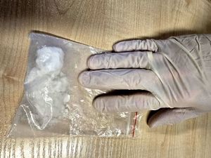 na zdjęciu biały proszek w foliowym worku na nim dłoń w białej rękawiczce