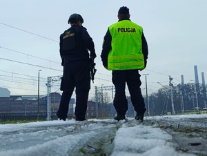 na zdjęciu policjant i funkcjonariusz Straży Ochrony Kolei stoją przy torowisku