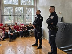 na zdjęciu dwóch policjantów przez nimi dzieci w mikołajowych czapkach
