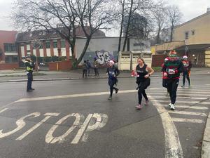 na zdjęciu policjant, obok ludzie biegnący w mikołajowych strojach
