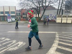 na zdjęciu mężczyzna w stroju elfa biegnie, obok stoi policjant