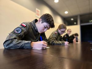 na zdjęciu uczniowie klas mundurowych siedzący przy stole i piszący test