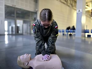 na zdjęciu uczennica wykonująca uciski na klatce piersiowej manekina