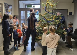 dzieci, ich opiekunowie i policjanci ubierający choinkę