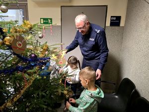 dzieci i policjant ubierający choinkę