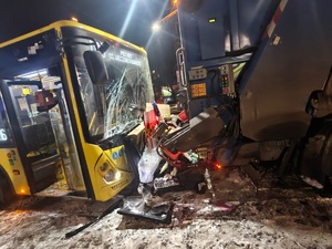 na zdjęciu kolizja dwóch pojazdów, przód autobusu z rozbitą szybą czołową, przed nim tył śmieciarki