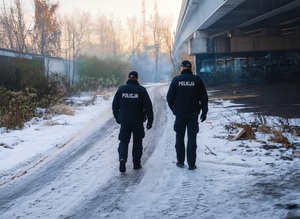 na zdjęciu dwaj policjanci idący obok wiaduktu