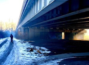 na zdjęciu wiadukt, obok w oddali idący policjant