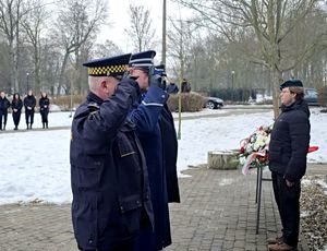 na zdjęci przed pomnikiem salutujący mundurowi